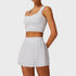 Front view of women’s white athletic tank top and pleated skirt set on model – Louvóre athleisure apparel