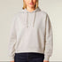 A woman wearing a beige mid-weight organic cotton hooded sweatshirt with dropped shoulders, a double-layered hood, flat drawcords, and ribbed cuffs.